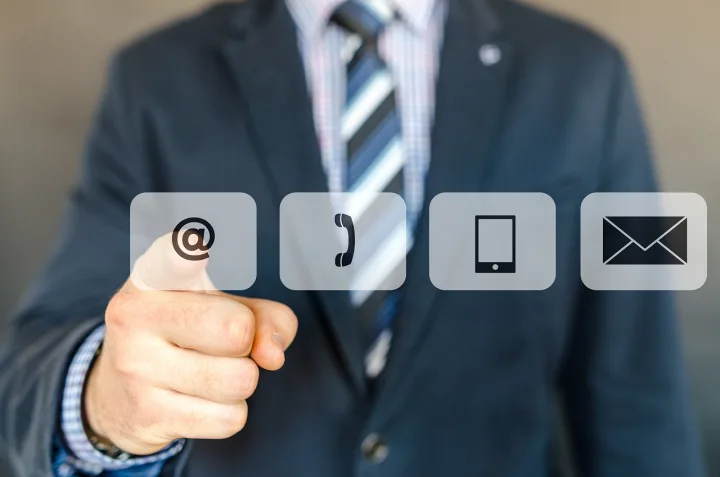 Hombre de traje señalando iconos de contacto: arroba, teléfono, móvil y sobre