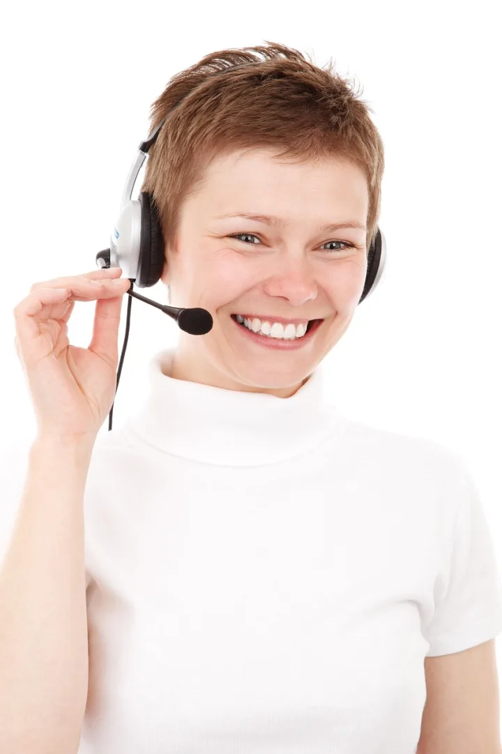 Asistente sonriente atendiendo una llamada con auriculares y micrófono